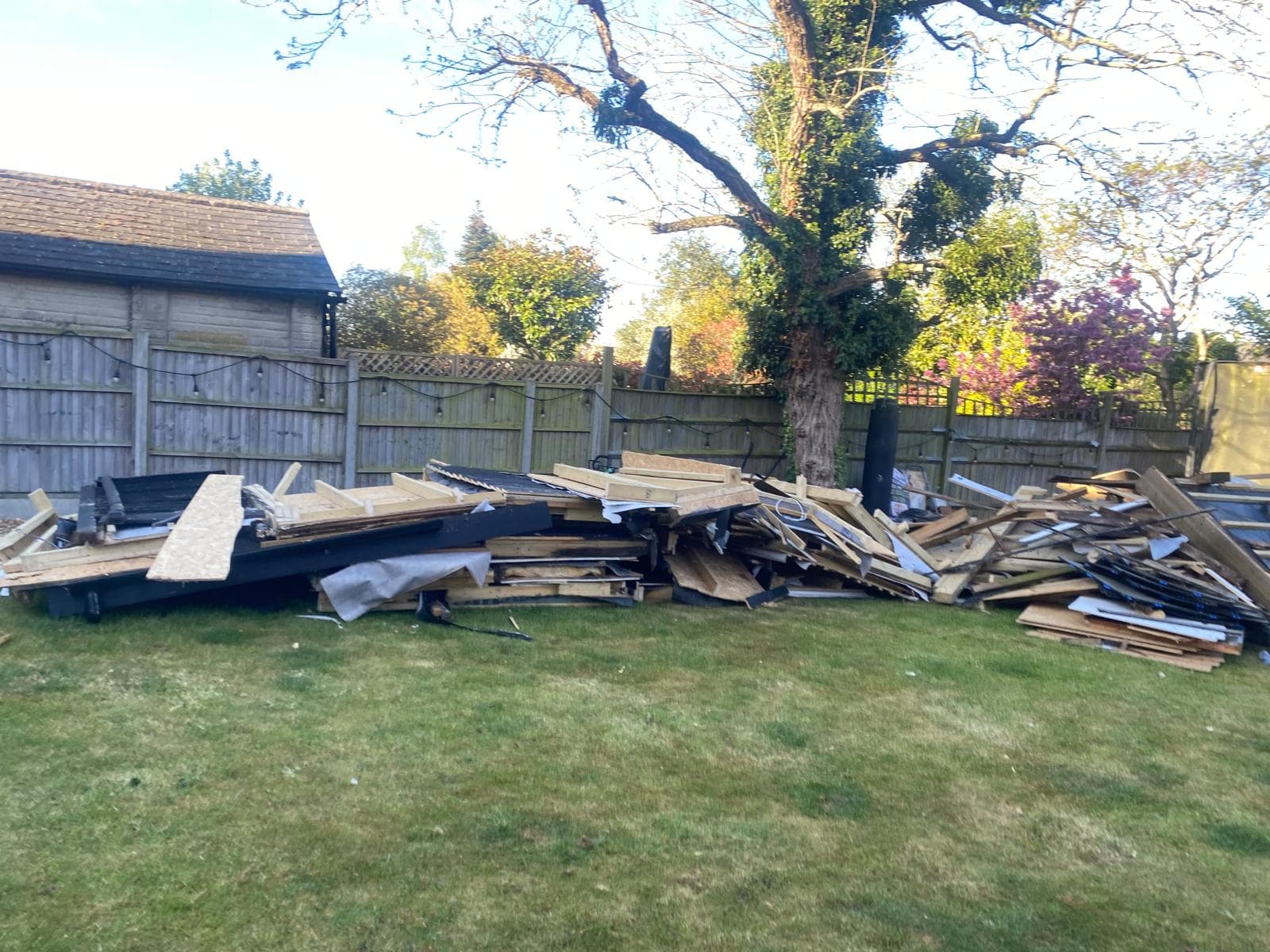 Large pile of fence panels and garden waste cleared from a lawn