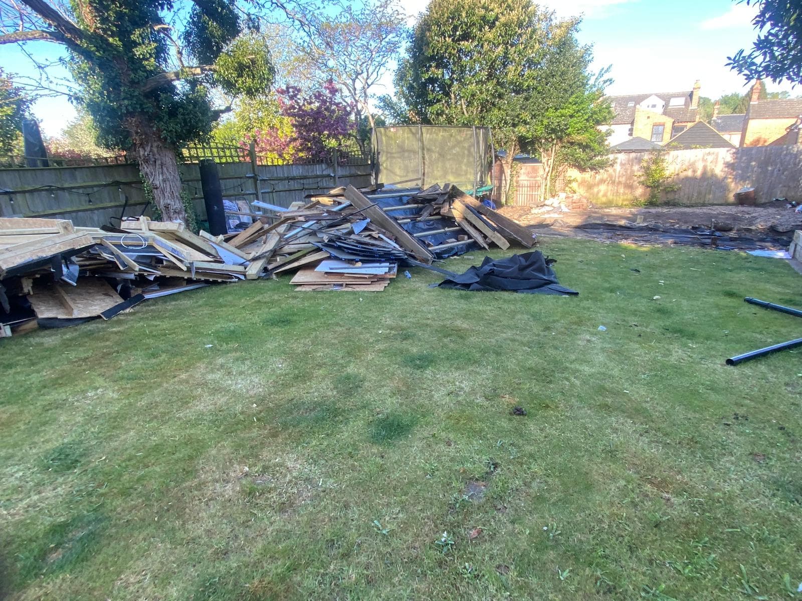Pile of broken fence panels and boards on a garden lawn