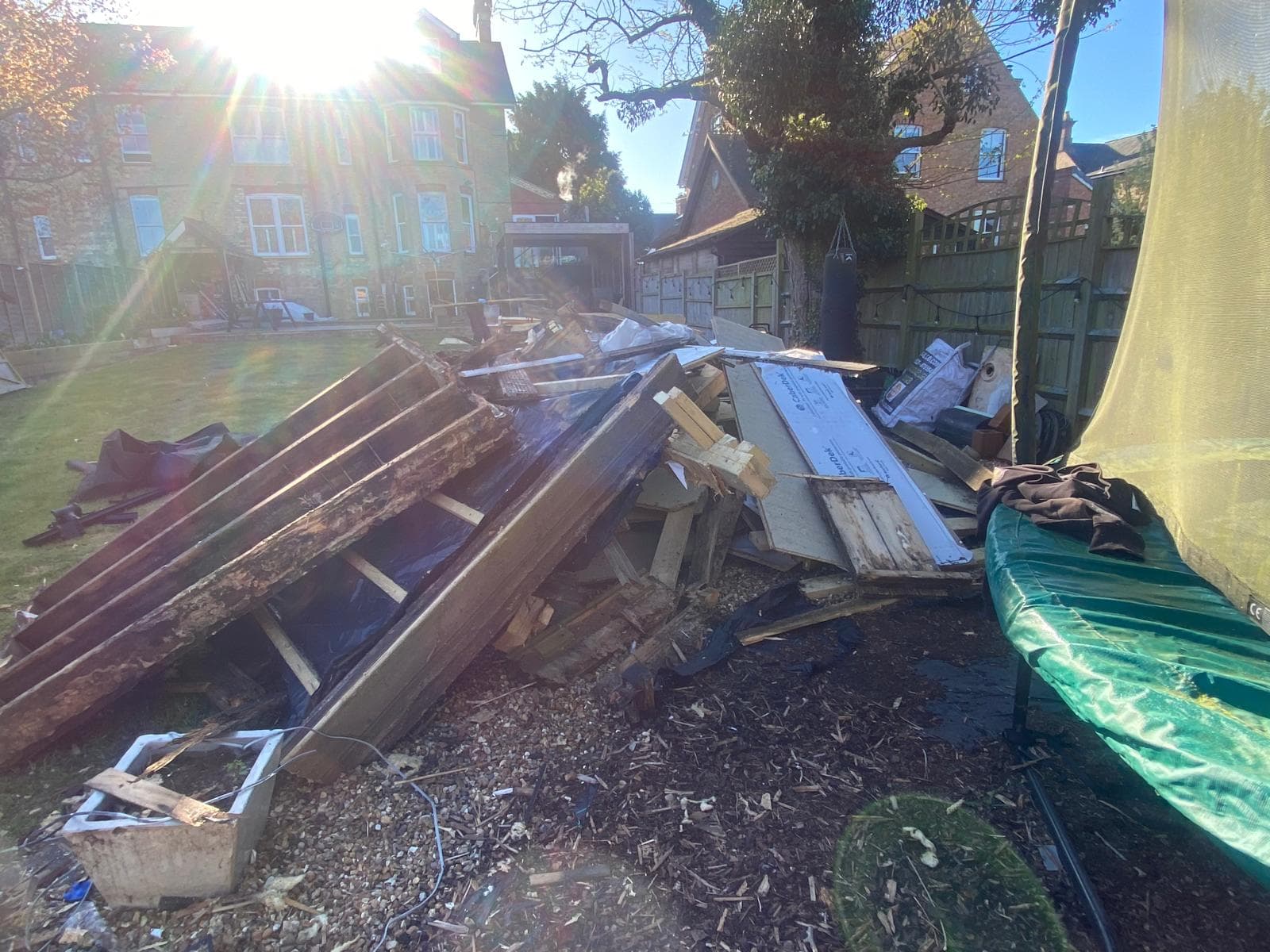Large pile of fence panels and timber next to a trampoline