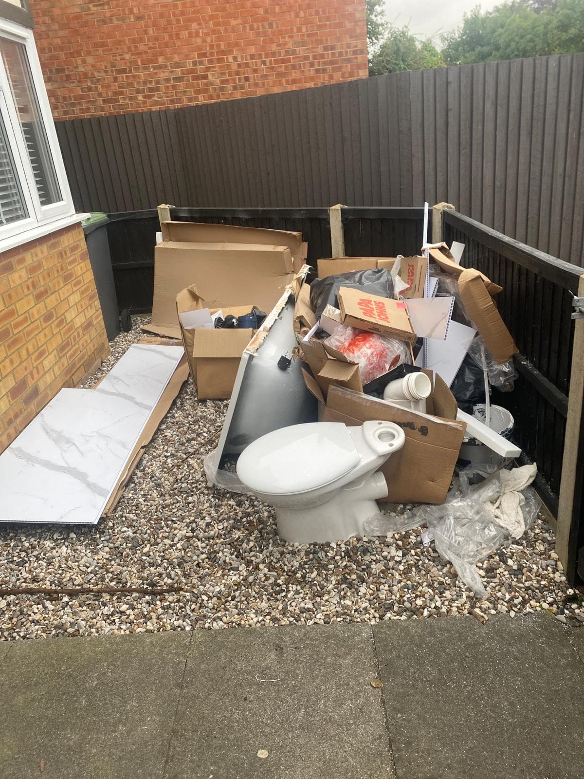 Old toilet, tiles and cardboard piled up ready for removal