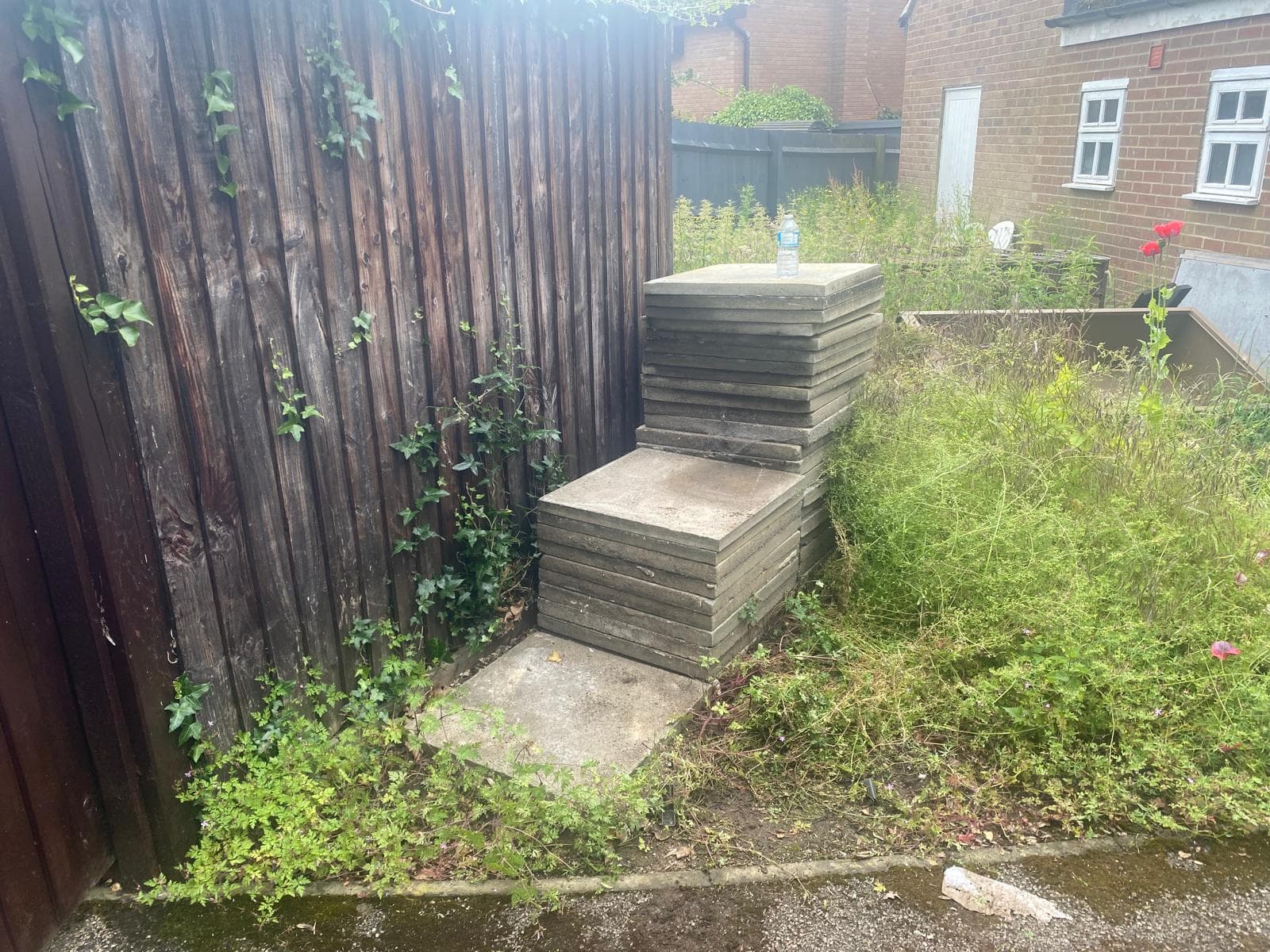 Paving slabs stacked against a fence ready for removal