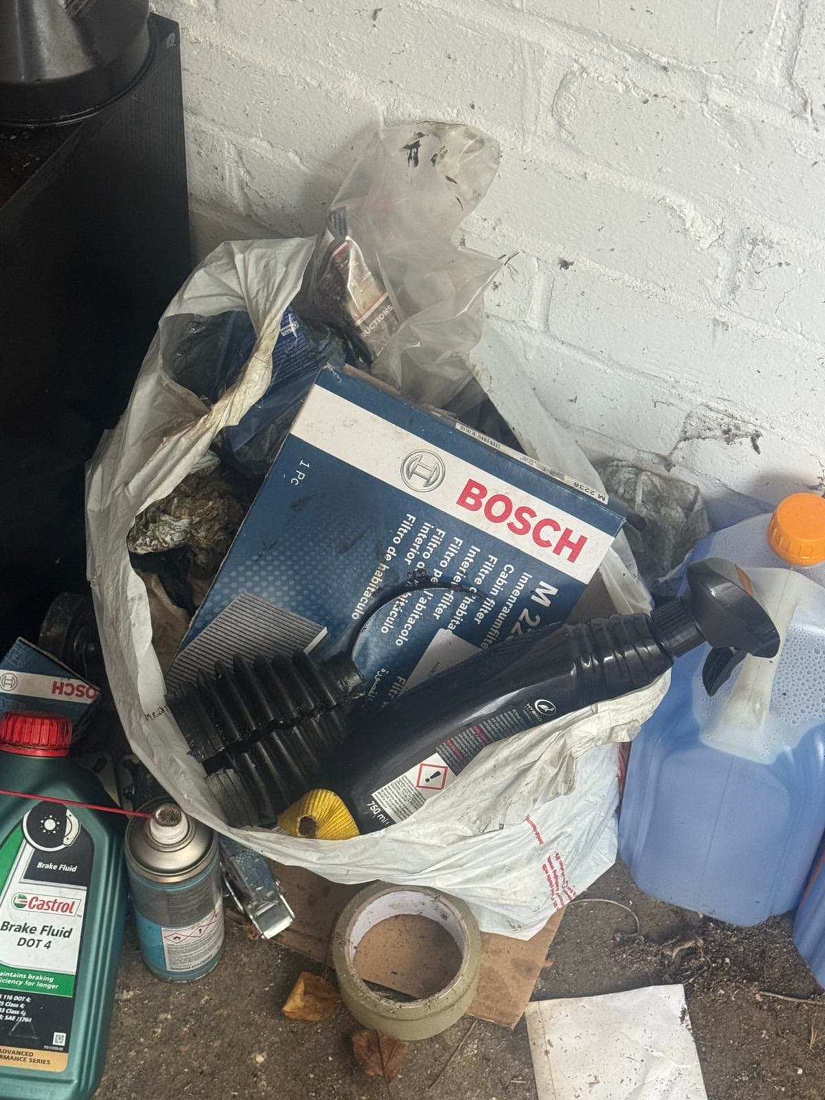 Bag of old car parts and fluids cleared from a garage