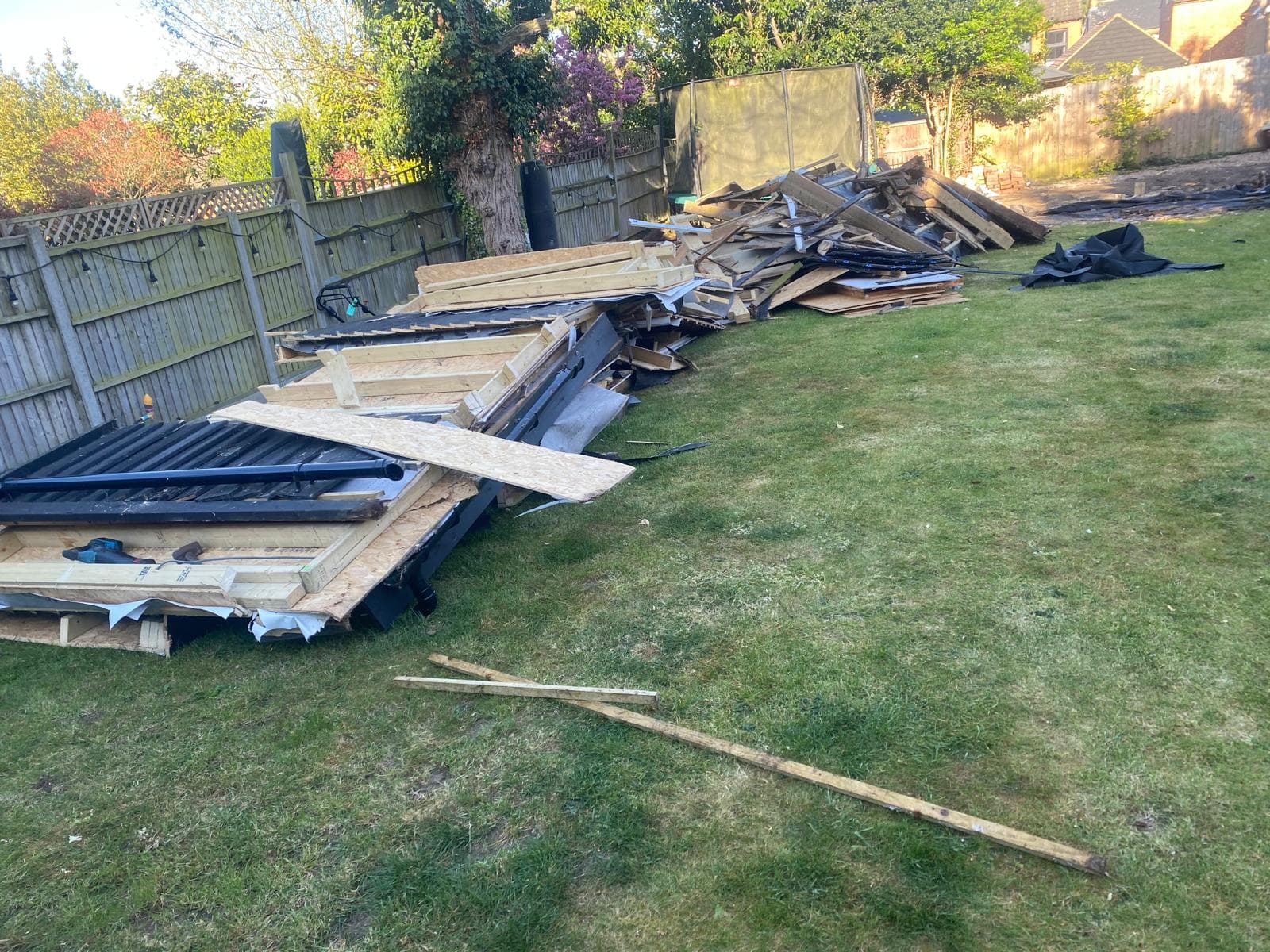 Broken fence panels and timber debris cleared from garden