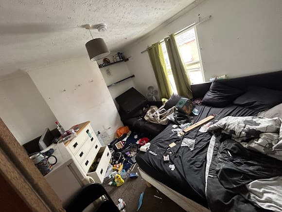 Cluttered bedroom before clearance